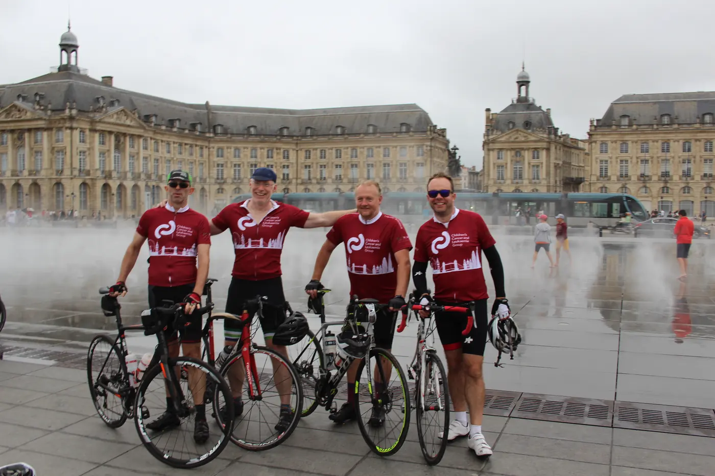 CCLG charity cyclists in matching red jerseys with their bikes at the Miroir d'eau in Bordeaux