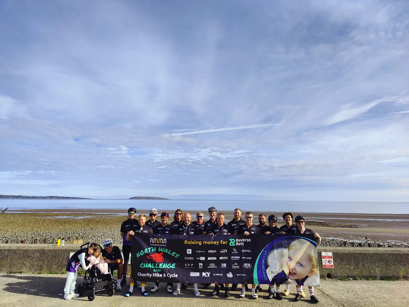 A Reverse Rett charity team with their banner on the North Wales coast at the start of their Sea to Summit challenge