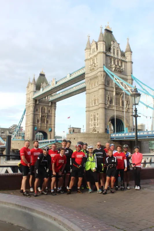 A charity cycling team in matching jerseys at Tower Bridge at the start of their London to Hamburg ride