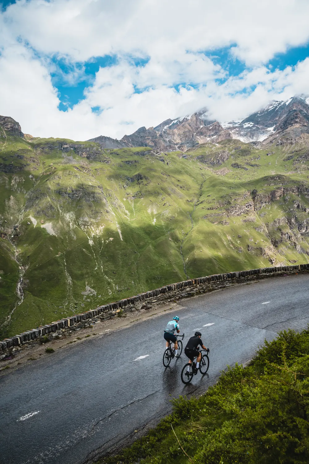 Two riders on a wet Alpine road