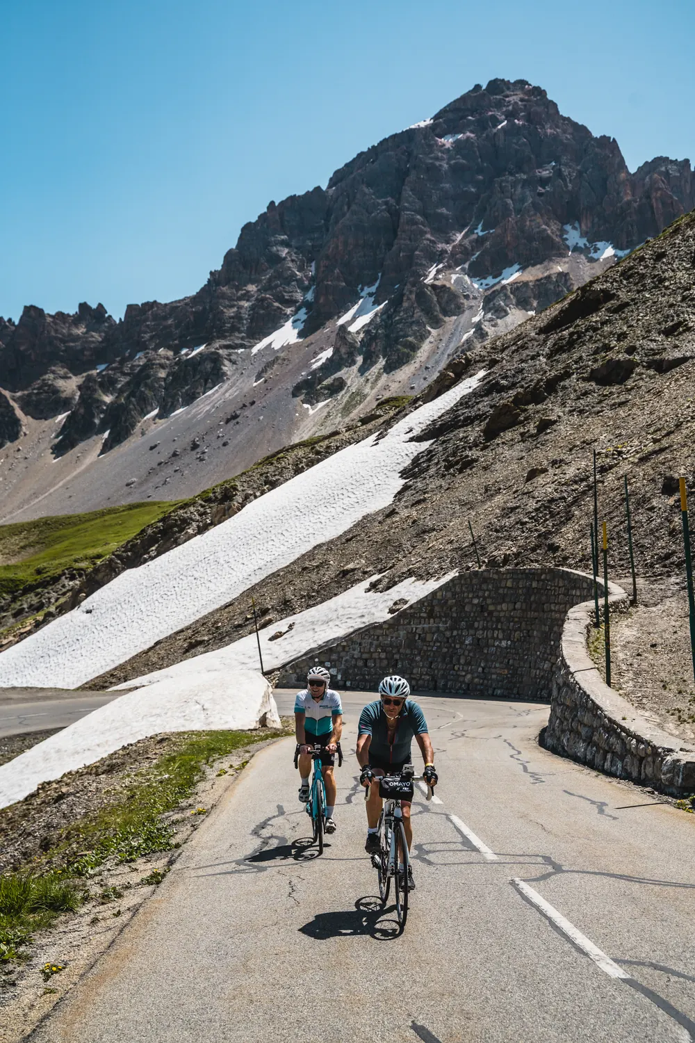 Riders climbing past snow between Valloire and Briancon