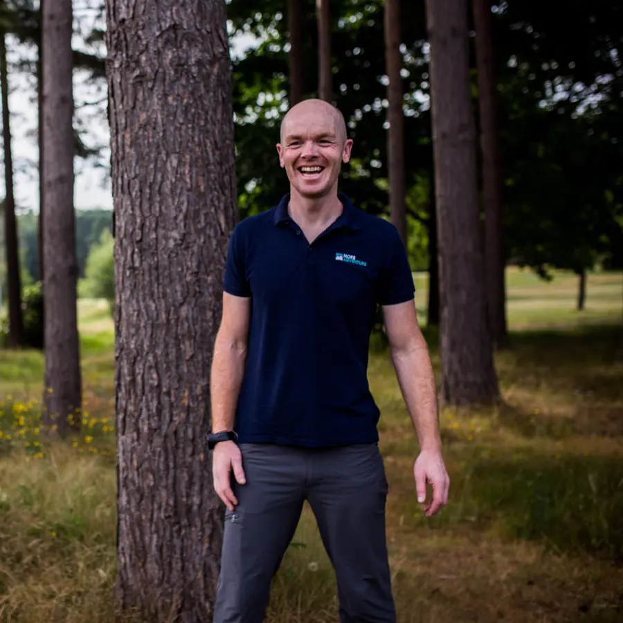 Tom Shooter, founder of More Adventure, smiling in a pine wood