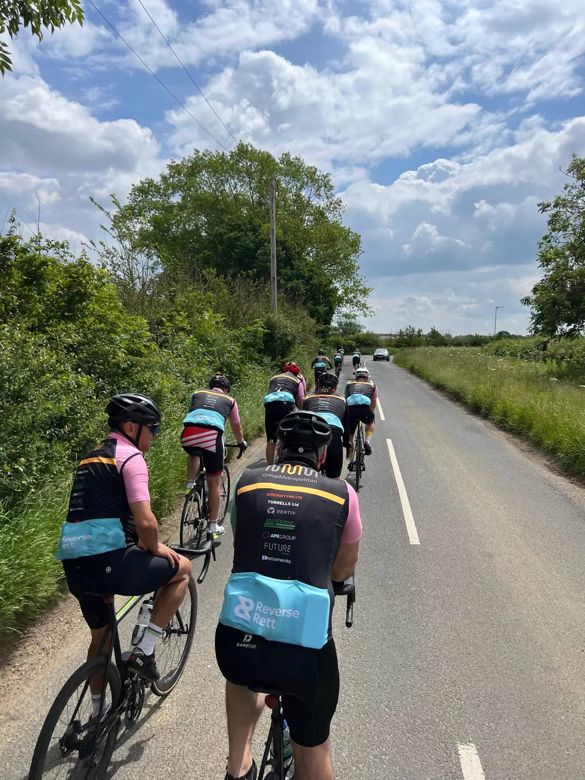 Charity riders in Reverse Rett jerseys riding in a line along a country lane
