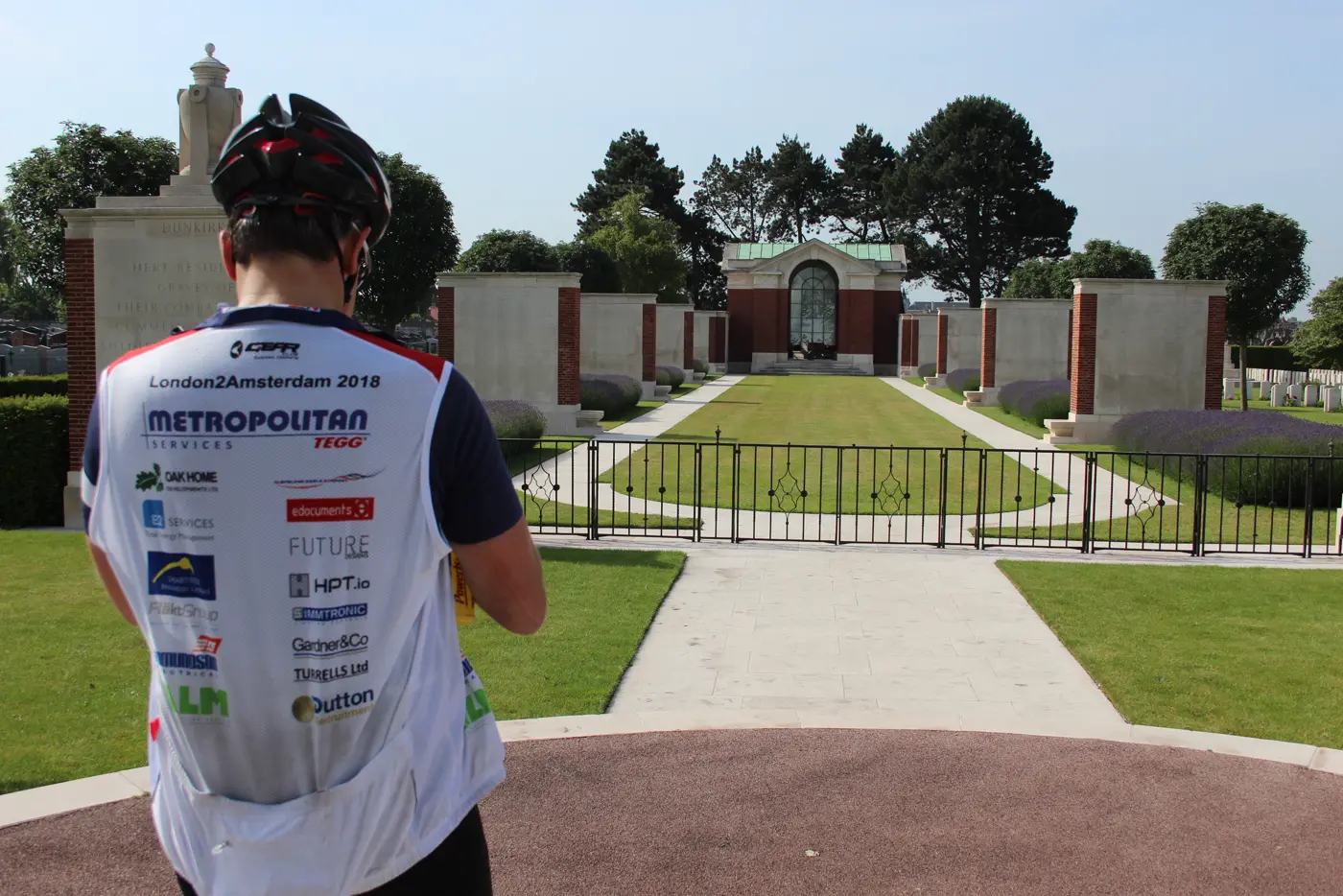 A rider in a sponsor-covered London2Amsterdam 2018 jersey at the Dunkirk memorial