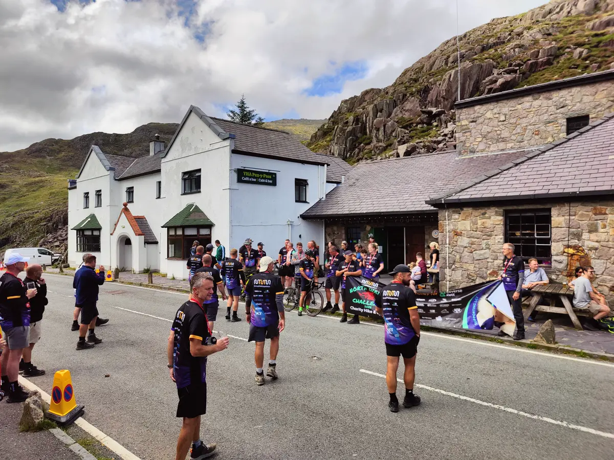 Group Metropolitan fundraisers in team jerseys at the Pen-y-Pass finish below Yr Wyddfa