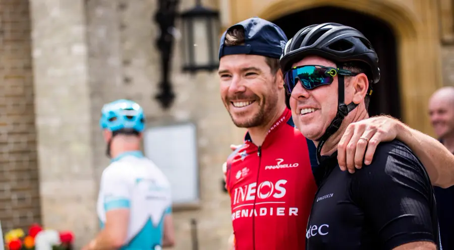 A professional cyclist in team kit sharing a laugh with a corporate rider