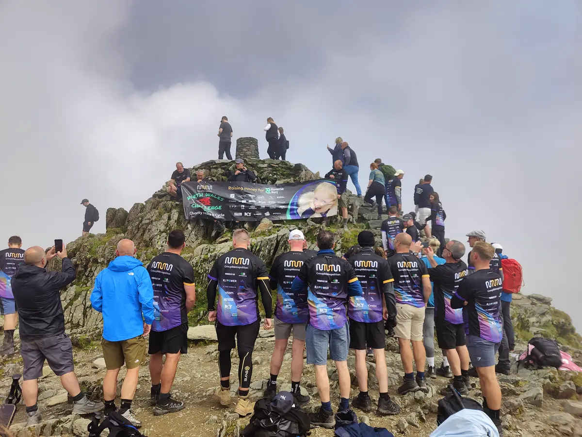 Fundraisers in team shirts gathered at the summit of Yr Wyddfa (Snowdon)