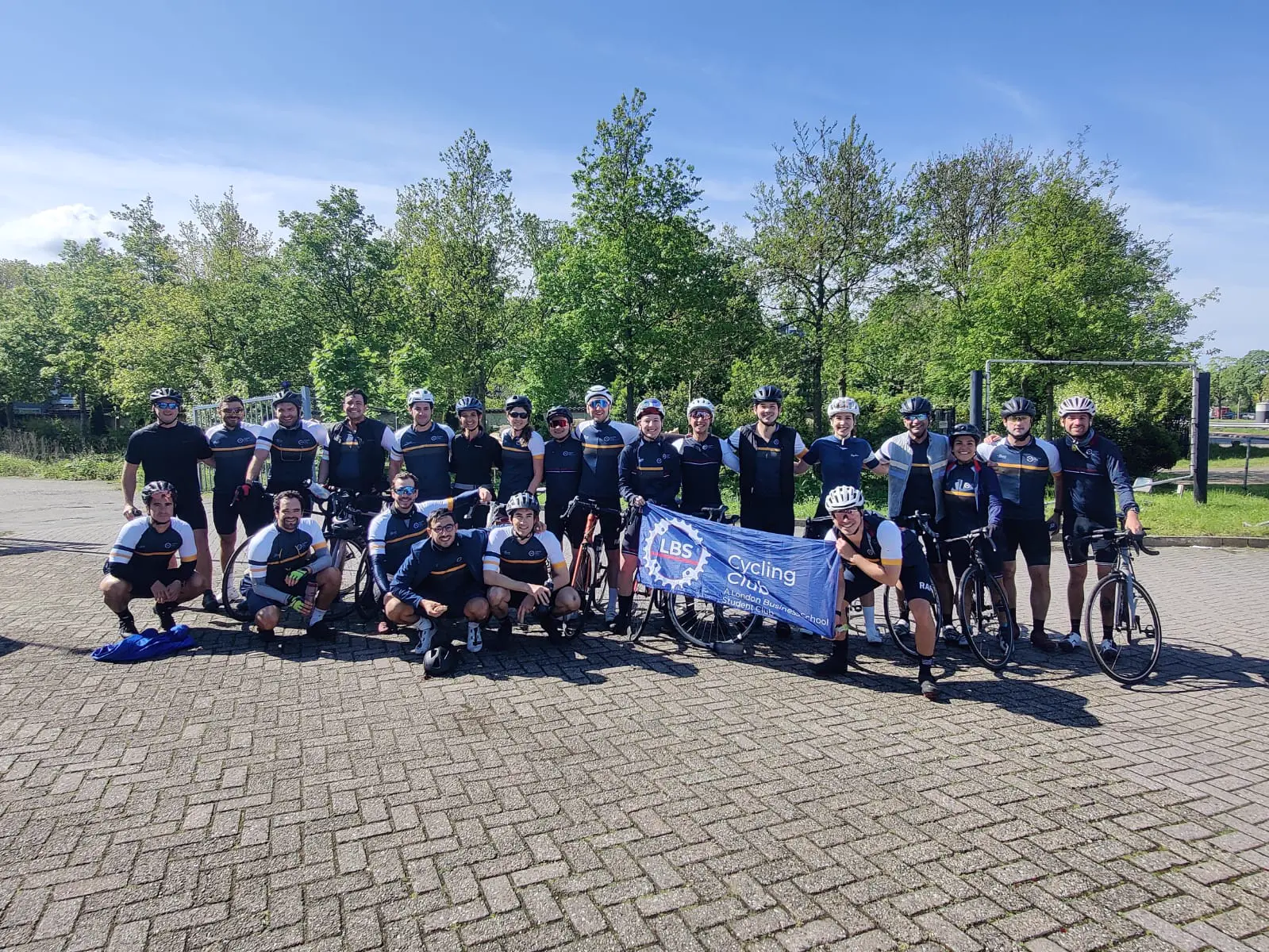 A large corporate cycling team lined up with their bikes and banner