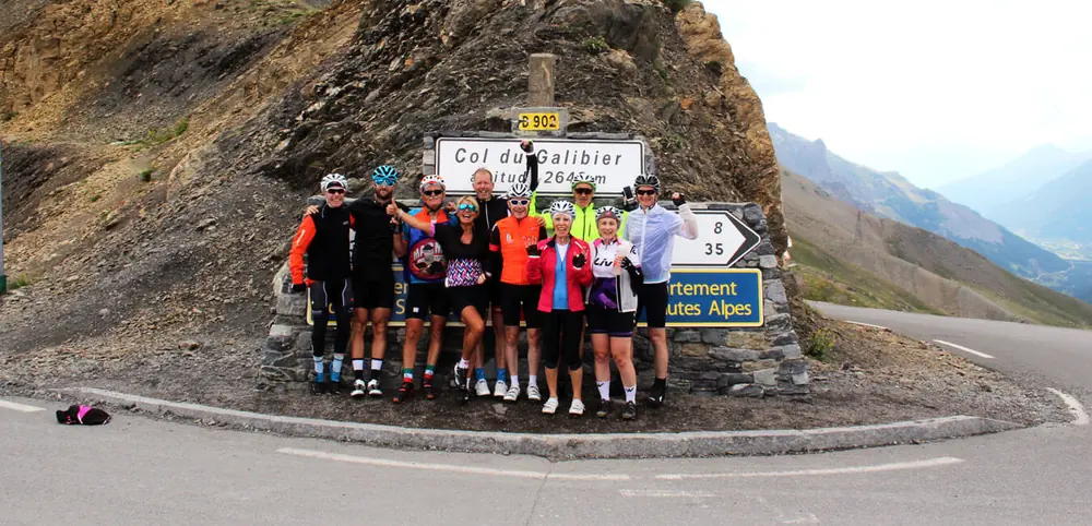 A group of riders at the Col du Galibier sign