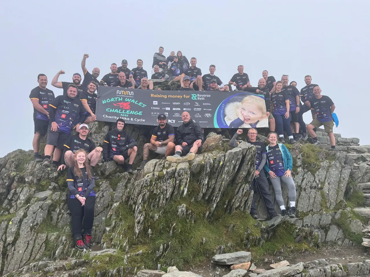A corporate charity team celebrating on the summit of Snowdon
