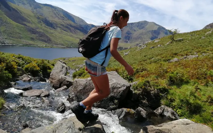 A hiker crossing a mountain stream in Snowdonia