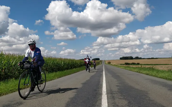 A cyclist on a long straight road through northern France