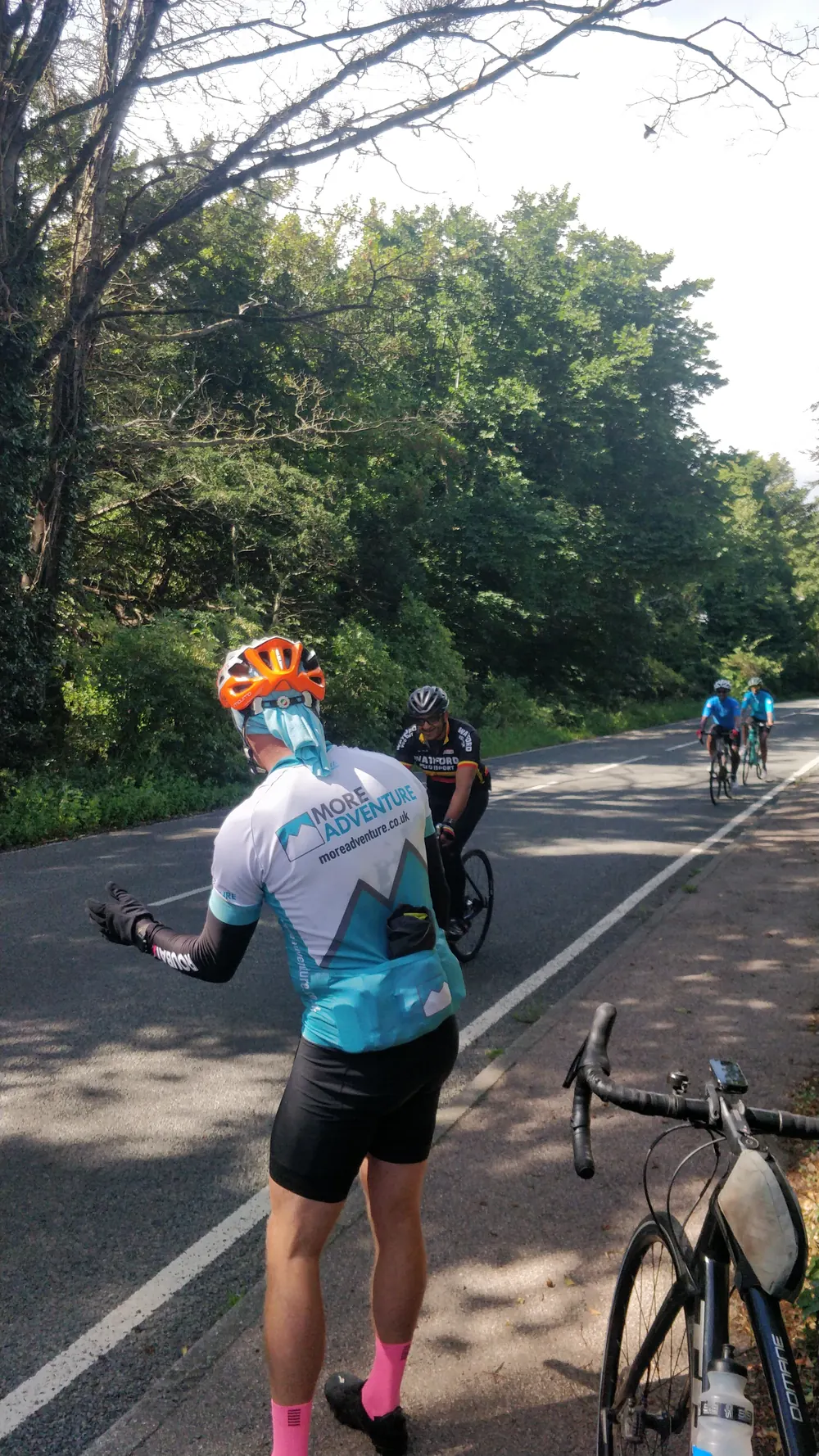 More Adventure leader Marcus Taylor waving riders through on a tree-lined road
