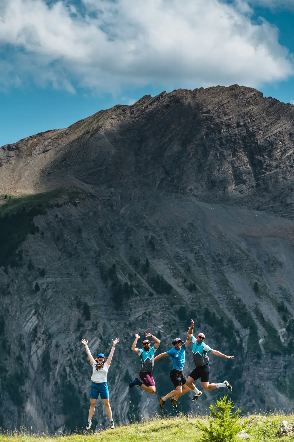 More Adventure leaders Hannah Lock, Rhys Jordan, Tom Shooter and Ben Coles jumping for joy in front of an Alpine peak